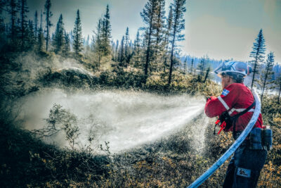 Un pompier de la Société de protection des forêts contre le feu arrose des arbres pour empêcher un retour de feu