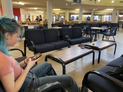 Une jeune étudiante de cégep patiente, seule, sur son téléphone