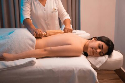 Une femme masse une autre femme sur le dos avec un rouleau de bois.