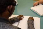 Une personne adulte qui lit un document en braille.