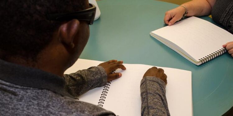 Une personne adulte qui lit un document en braille.